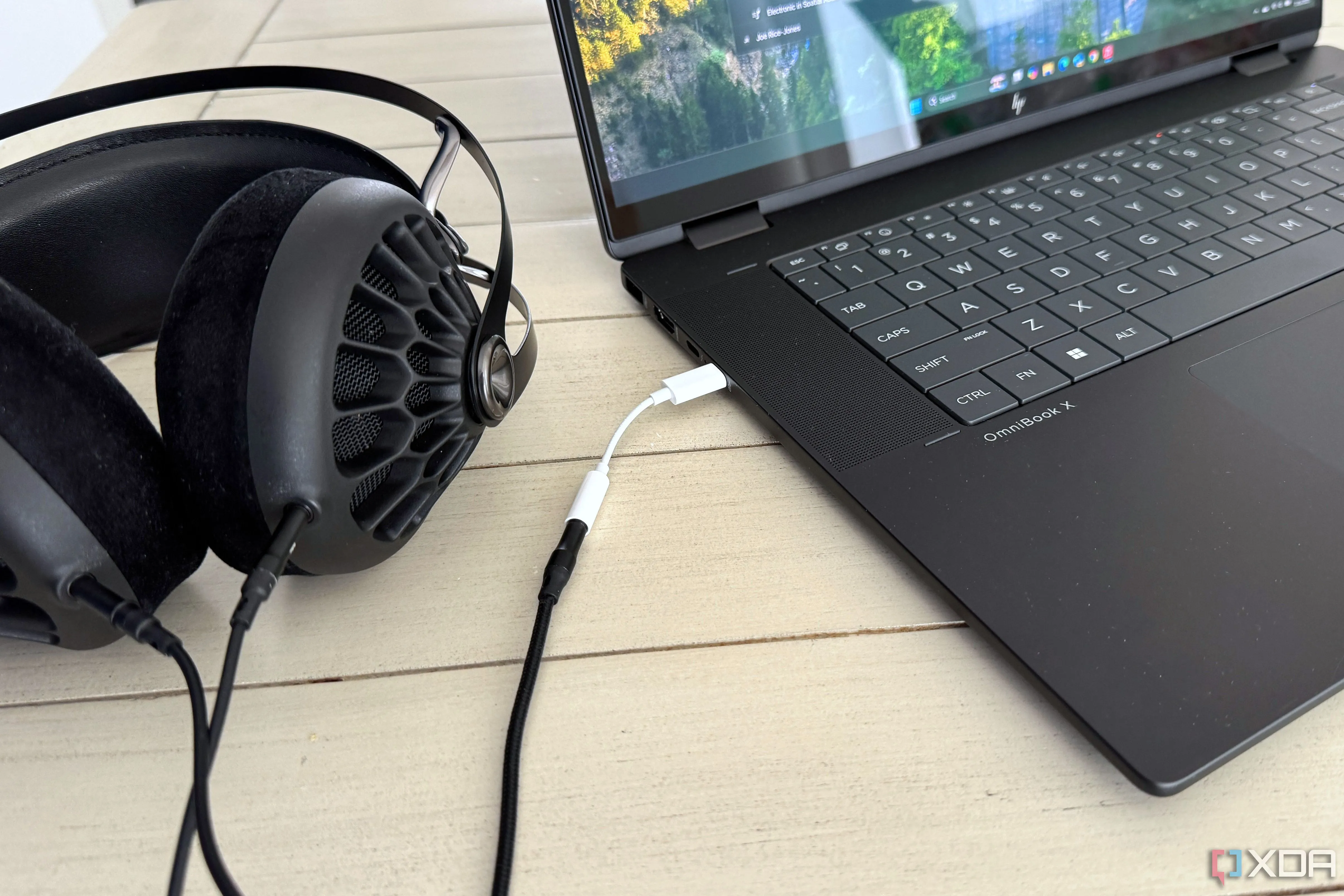 Bộ chuyển đổi Apple USB-C sang 3.5mm được cắm vào cổng USB-C của laptop, thể hiện sự tiện lợi khi sử dụng