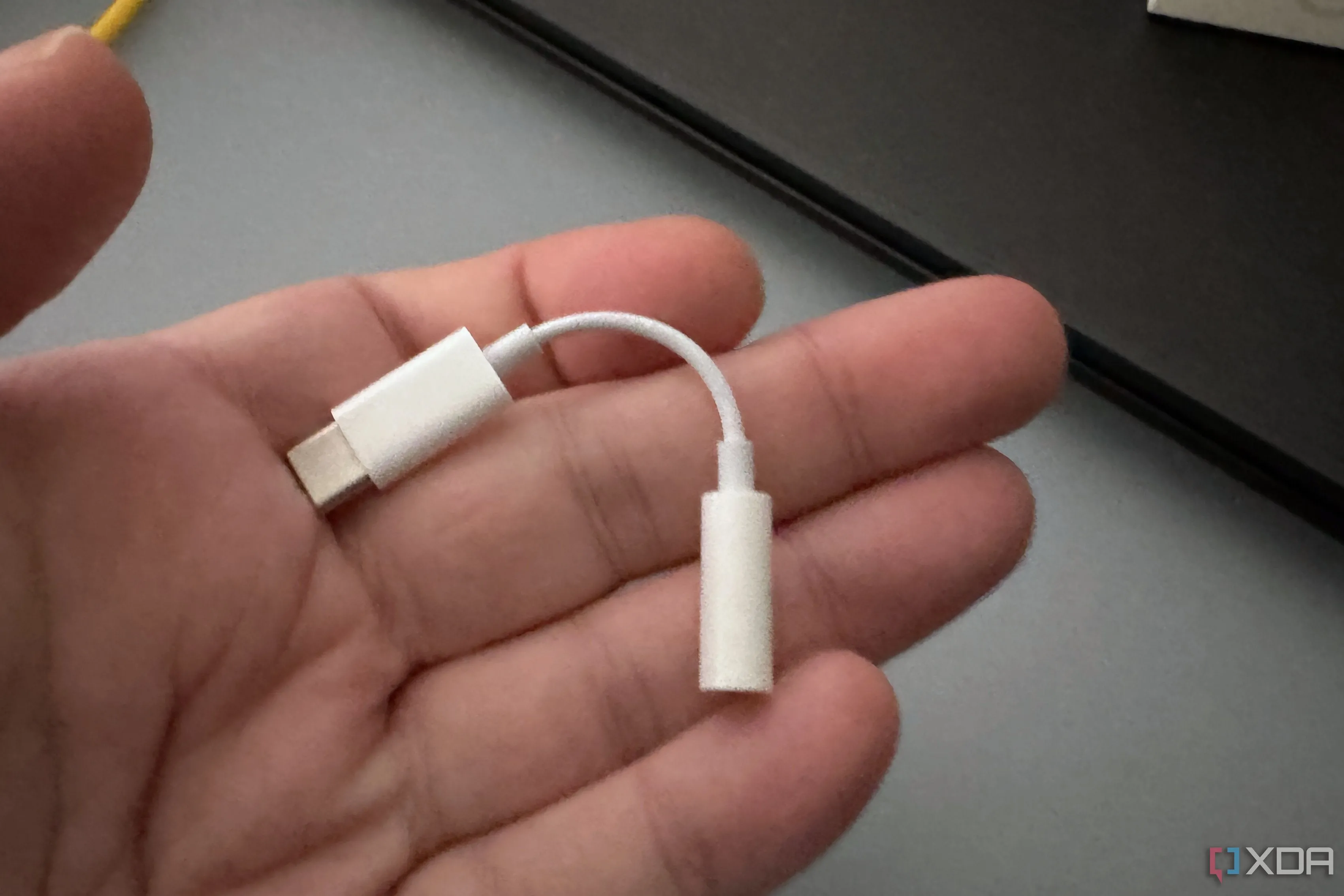 Bộ chuyển đổi Apple USB-C sang 3.5mm nằm gọn trong lòng bàn tay, minh họa kích thước nhỏ gọn