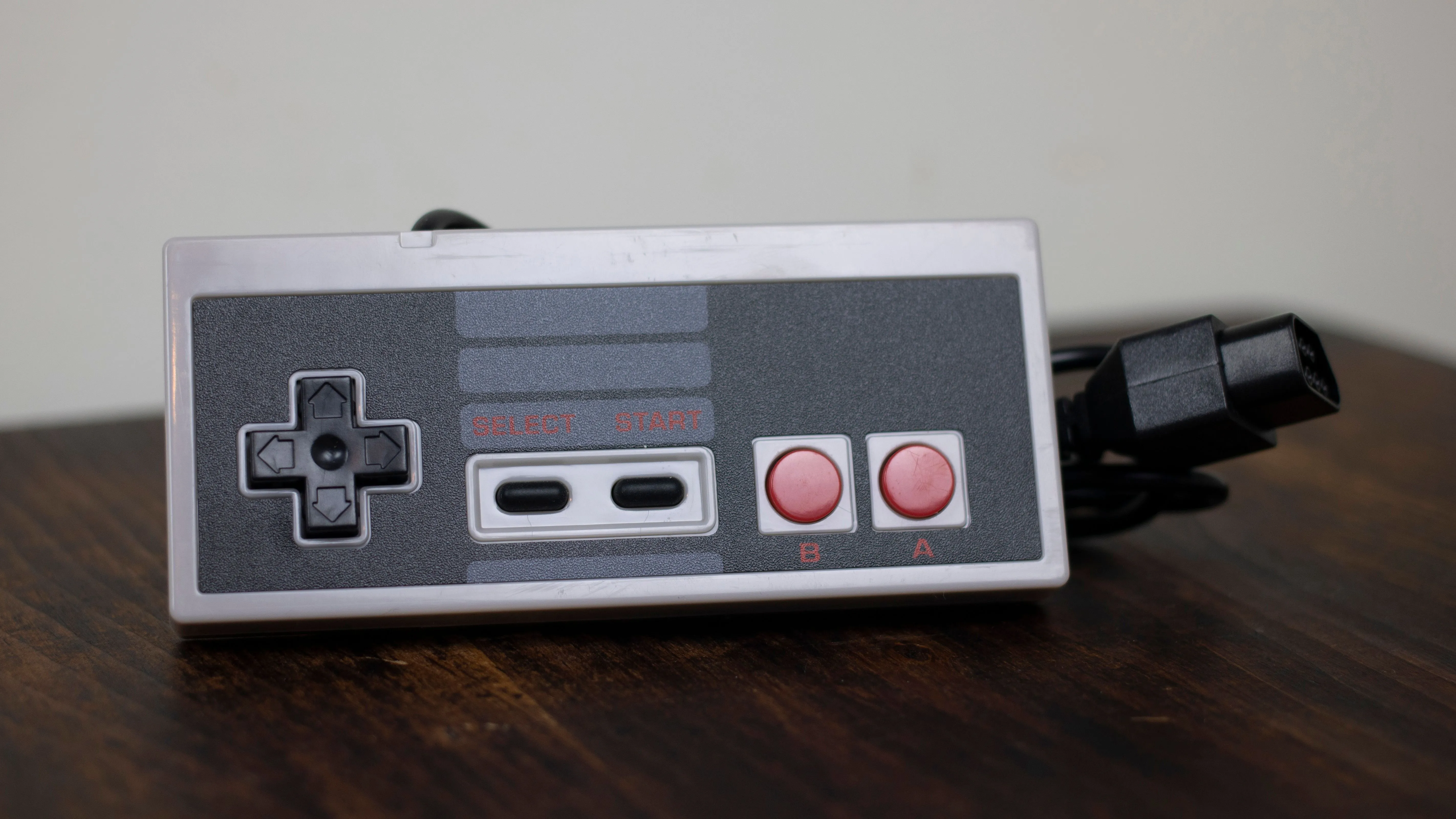 Hình ảnh cận cảnh một tay cầm NES Classic của bên thứ ba đặt trên mặt bàn gỗ.