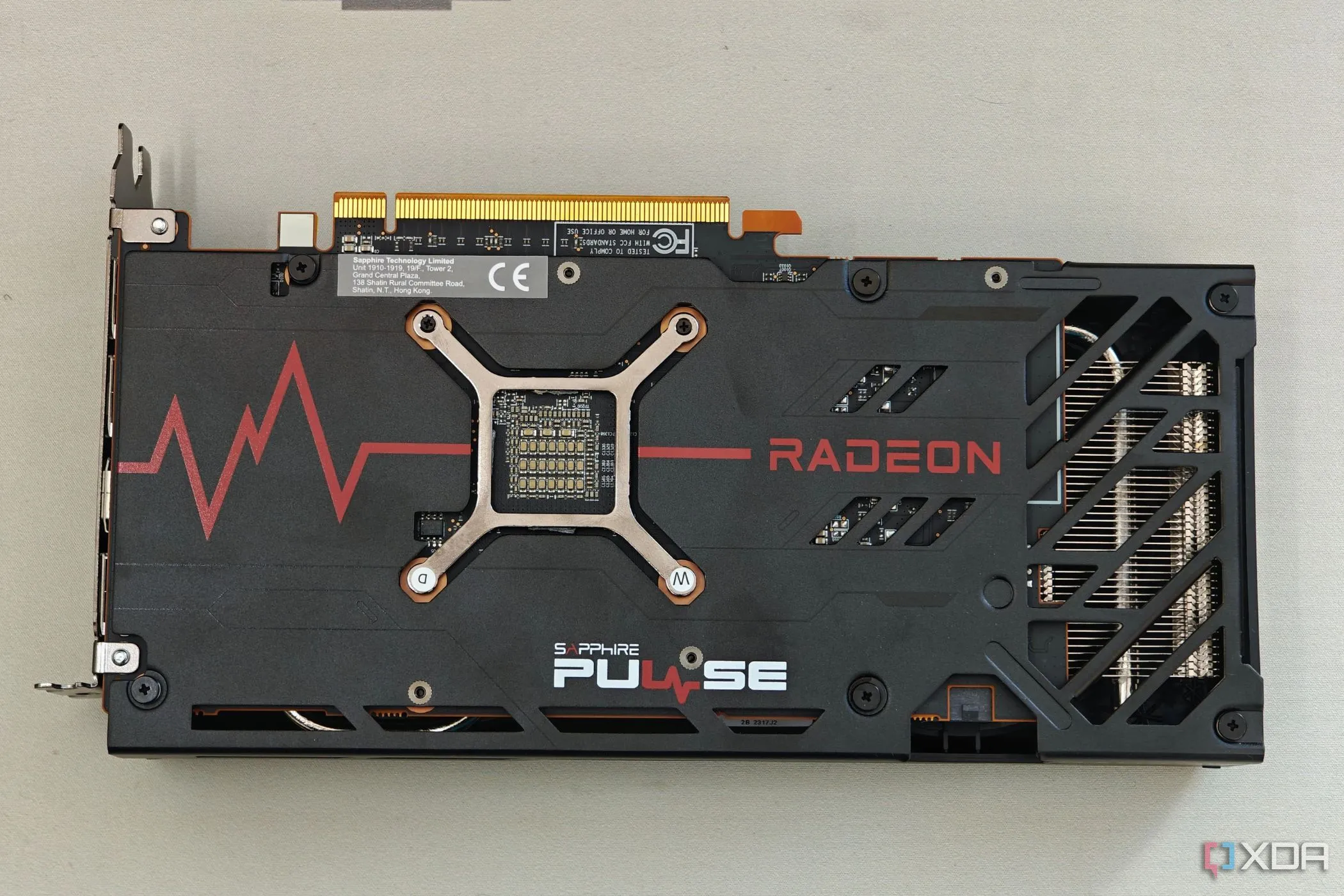 Hình ảnh mặt sau (backplate) của card đồ họa AMD Radeon RX 7600 Pulse OC, minh họa việc sử dụng vật liệu nhựa kém hiệu quả cho tản nhiệt.