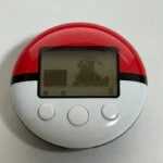 Hình ảnh máy đếm bước PokeWalker với Pokémon Dragonite trên màn hình, phụ kiện của game Pokémon SoulSilver và HeartGold trên Nintendo DS.