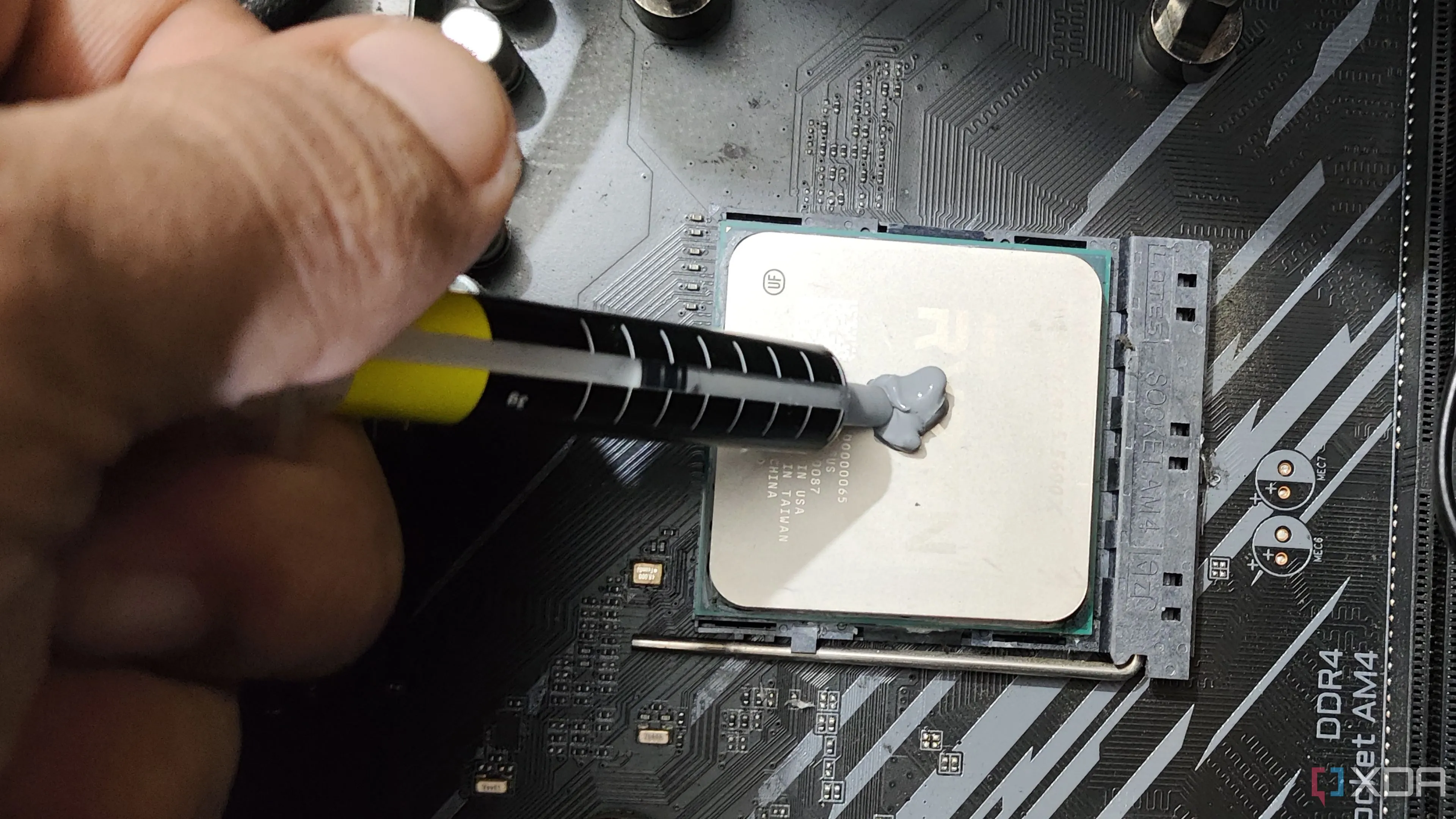 Hình ảnh một người đang bôi keo tản nhiệt mới lên CPU AMD Ryzen 5 5600X