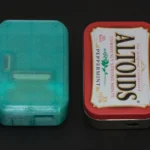 Máy chơi game Pi Tin đặt cạnh hộp kẹo Altoids, minh họa kích thước nhỏ gọn của console Raspberry Pi
