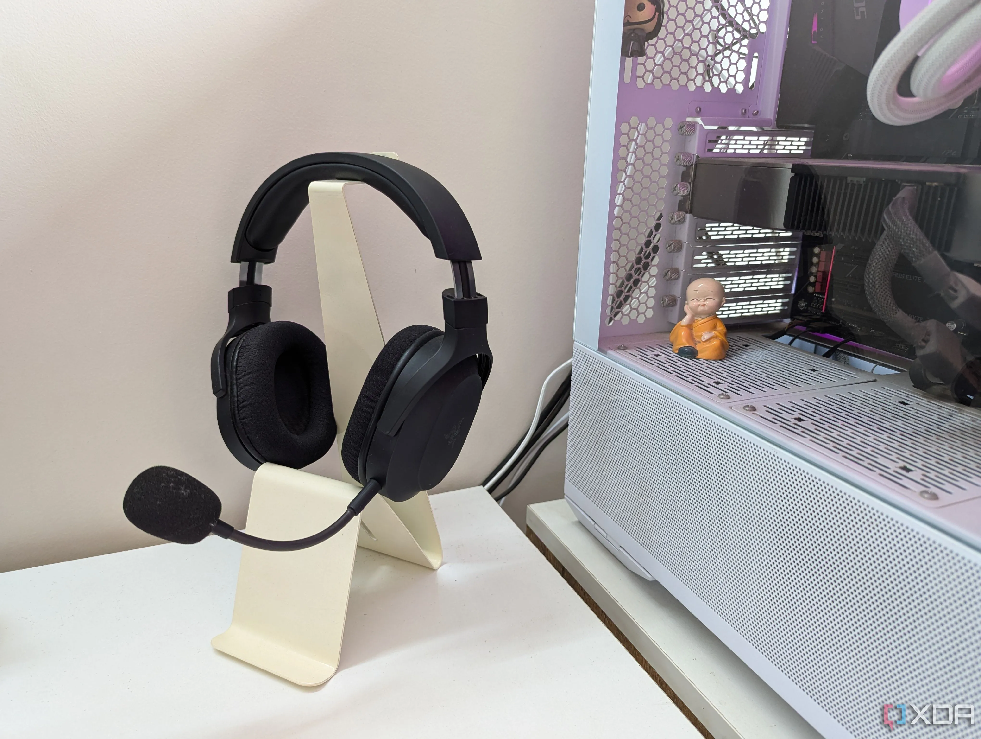 Tai nghe gaming trên giá đỡ cạnh PC gaming trên bàn trắng